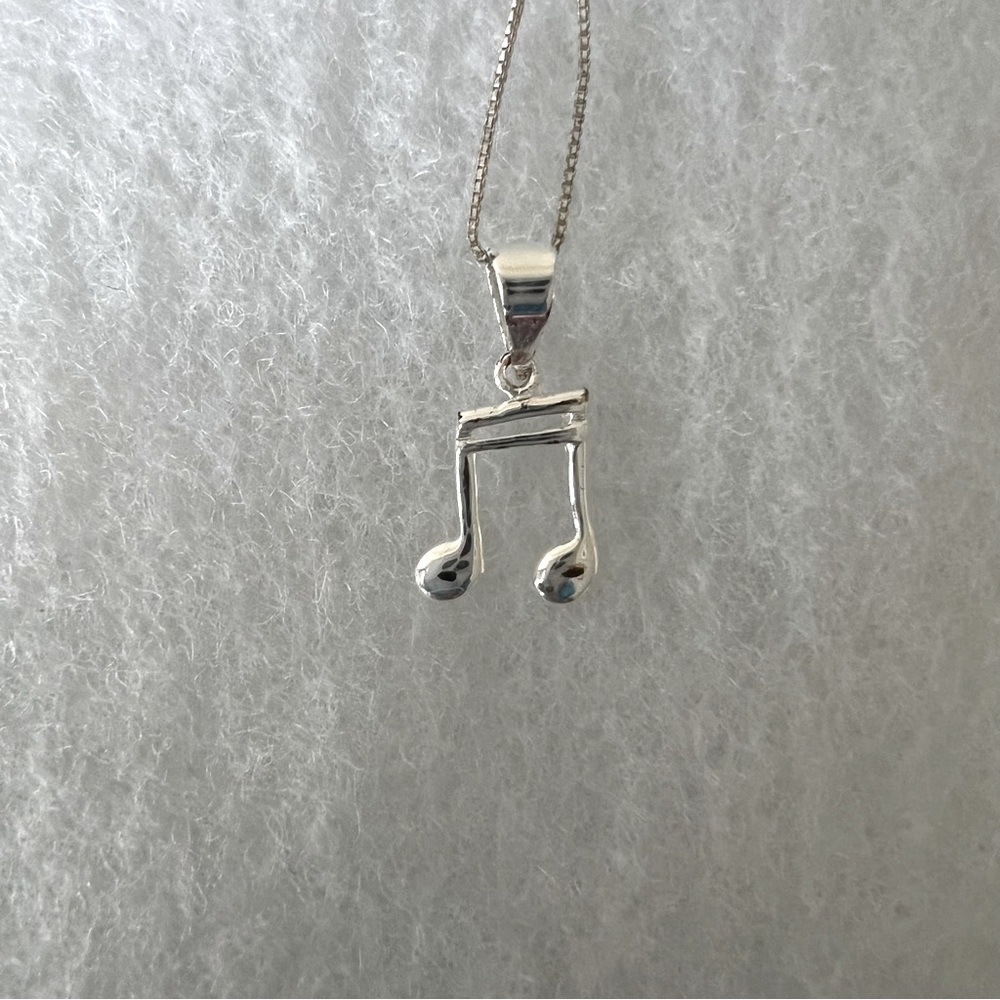 Stainless steel "half-note" emblem necklace.